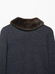 Detail view showing thick brown faux fur collar and shoulder seam of grey knit jacket
