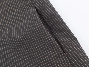 Macro detail of dark plaid fabric texture and seamless side pocket stitching on jacket