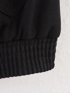 Detail shot of the elastic ribbed hem and knit texture on a black jacket