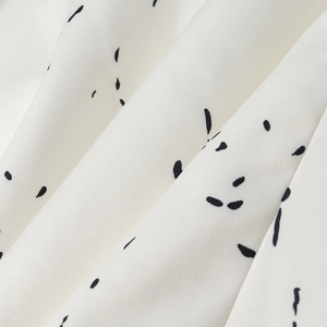 Close-up of white twill fabric with black abstract graffiti and textured fiber details
