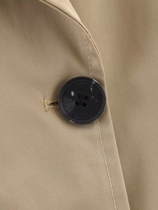 Detail of khaki twill trench coat showing a black marble pattern button and clean stitching