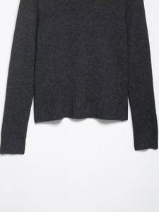 Detailed close-up of dark grey knit texture and ribbed hem on a long sleeve jacket