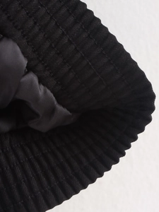 Close-up of black ribbed knit cuffs and smooth lining on a loose jacket garment