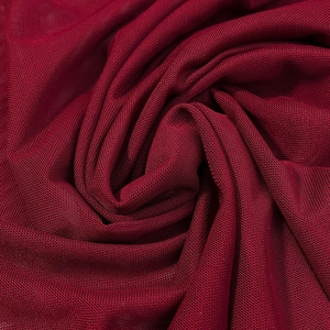 Gros plan détaillé du tissu en maille rouge foncé avec plis doux et texture translucide