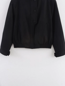 Close-up of black button closure, elasticated hem and side pockets on a casual jacket
