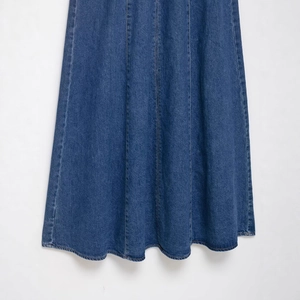 Detailed lower half of a dark blue wash denim dress with vertical topstitching and A-line cut