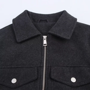 Detail of dark grey wool-like jacket featuring a metal zipper and dual flap pockets