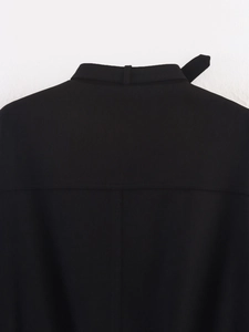 Detail of high collar and back yoke stitching on black loose-fit jacket with twill texture