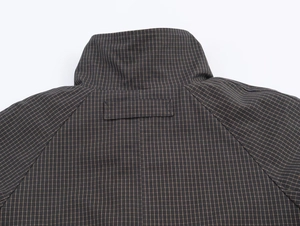 Detail of high stand collar and raglan sleeve on a dark brown checkered jacket