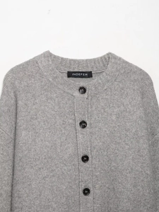 Close-up of grey knit cardigan with round neck and black buttons on white background