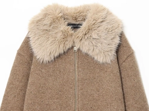 Detailed macro view of the large faux fur collar and metal zipper on the brown jacket