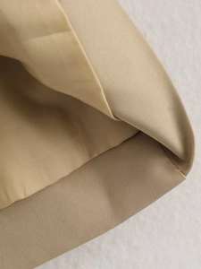 Close-up of khaki twill fabric showing premium stitching on short trench coat edges