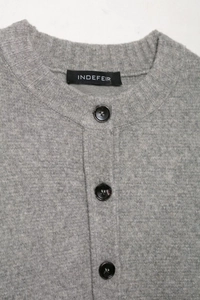 Close-up of grey knit cardigan showing round neck, black buttons, and soft fabric texture