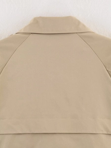 Detailed view of the khaki trench jacket collar and raglan sleeve stitching on white background
