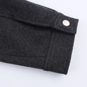 Detail of dark grey wool jacket cuff with metallic snap button and premium stitching