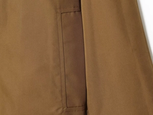 Detailed close-up showing the precise stitching on the pocket of the khaki trench coat