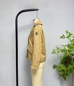 Detail of khaki trench coat featuring shoulder epaulettes and buttoned cuff straps