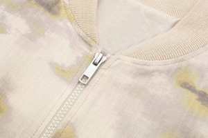 Détail de fermeture éclair argentée et col côtelé sur veste bomber camouflage
