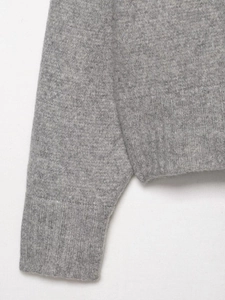 Close-up of soft light grey knit sweater showing high-quality ribbed cuffs and texture