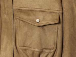 Detail of camel suede jacket showing flap pocket with matte silver metal snap button