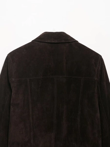 Detail view of the back of a dark brown suede jacket showing stitching and velvet texture
