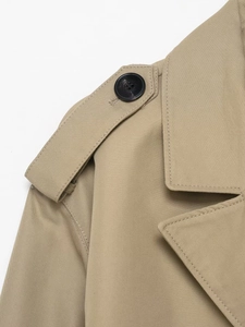 Macro shot of khaki trench coat shoulder straps with button and fine twill texture detail
