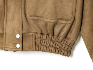 Detail of brown faux suede jacket featuring elastic hem and silver metal snap buttons