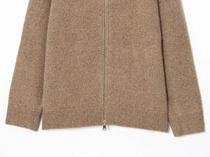 Detail of camel heathered knit cardigan featuring a silver metal zipper and ribbed cuffs