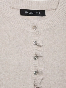 Detailed macro view of the knitted texture and pearlescent buttons on a beige cardigan