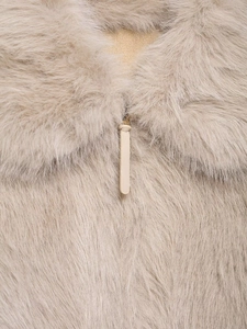 Close-up of fluffy faux fur texture and metal zipper with leather pull on jacket