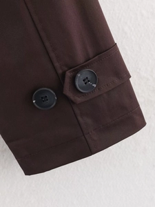Detailed view of dark brown trench coat cuffs featuring adjustable buttons and premium stitching