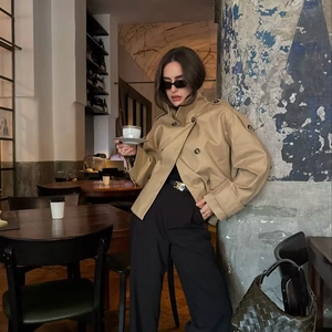 Close-up of a khaki short trench coat with double-breasted buttons and epaulettes detailing