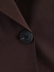 Detail of a brown double-breasted short trench coat showing button and twill fabric texture