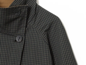 Detail of high collar and dark plaid fabric with matte buttons on a minimalist coat