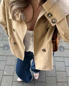 Chic khaki short trench coat with double-breasted buttons and wide lapel on model