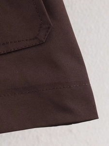 Detailed close-up of dark brown twill fabric with pocket flap and premium double stitching