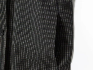 Macro detail of dark plaid fabric texture with side pocket and button on reversible coat