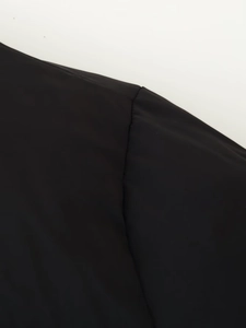 Close-up of black polyester jacket showing shoulder stitching and patchwork detail