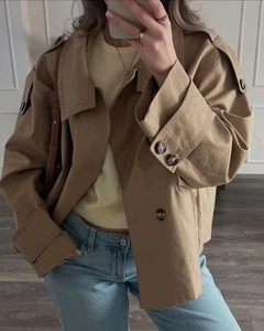 Detail of short khaki trench coat with double-breasted buttons and classic epaulettes