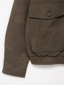 Detail of dark brown faux suede jacket featuring a large flap pocket and ribbed hemline