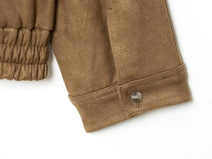 Detail of brown suede bomber jacket showing silver metal button and elastic hem stitching