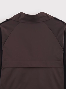 Detail of dark brown short trench coat showing epaulettes and raglan sleeve design