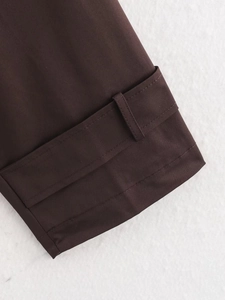 Macro view of dark brown trench coat sleeve with adjustable cuff straps and fine stitching