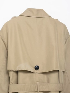 Detailed view of the back storm flap and button on a classic khaki trench coat