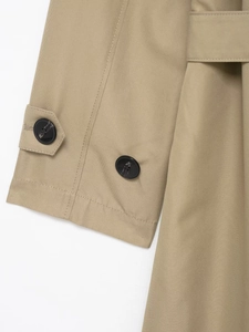Detailed macro view of khaki trench coat cuffs featuring adjustable straps and resin buttons