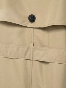 Detail of khaki trench coat featuring a black resin button and high-quality stitching