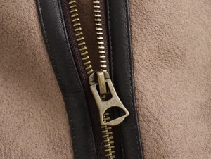 Dettaglio macro della zip in bronzo con bordo in pelle su giacca scamosciata marrone