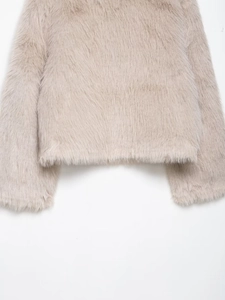 Detailed close-up of fluffy faux fur texture and hemline on a beige plush jacket