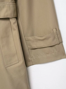 Detailed macro view of khaki trench coat sleeve with cuff strap and fine twill fabric texture