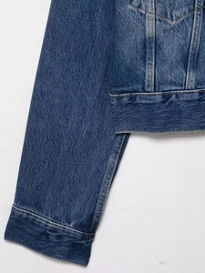 Close-up of deep blue denim jacket with orange contrast stitching and textured fabric